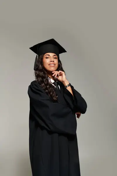 A confident young woman in graduation attire poses with a smile, exuding pride and joy. — Stock Photo