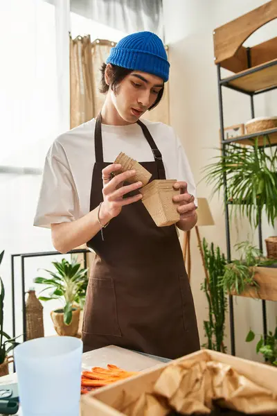 Young man carefully transplanting plants in a sunlit studio filled with greenery and life. — Stock Photo