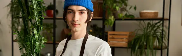 Young man in casual attire engages in the art of transplanting green plants in a sunny studio. — Stock Photo