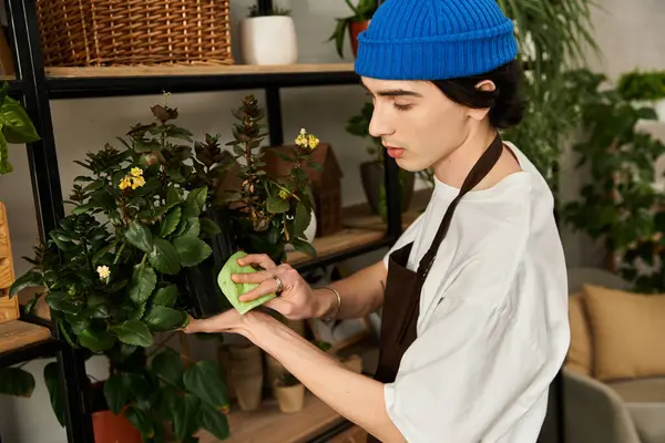 Young man nurtures lush plants in a welcoming studio space. — Stock Photo