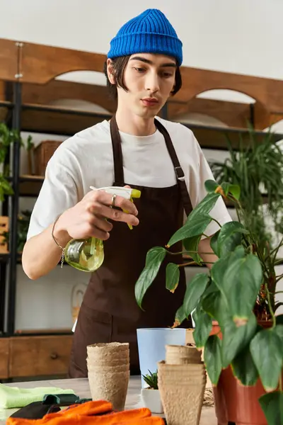 Young man cares for plants in a bright studio, demonstrating his passion for gardening and growth. — Stock Photo