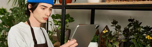 Handsome young man focused on transplanting indoor plants in a well organized studio space. — Stock Photo