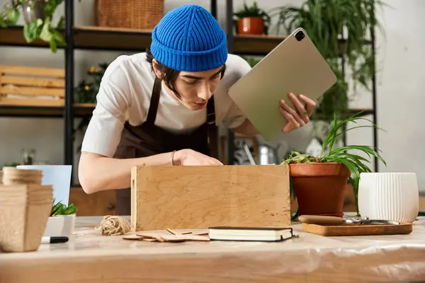 A young man intently transplants plants in his green filled modern studio workspace. — Stock Photo