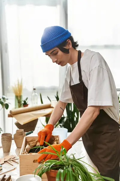 A young man carefully transplanting plants in a well lit studio, showcasing his love for gardening. — Stock Photo