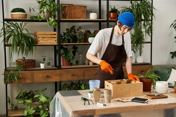 Young man transplanting greenery amid lush plants and bright natural light. — Stock Photo
