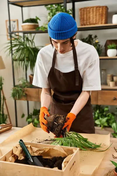 Handsome young man carefully transfers plants into new pots while surrounded by greenery. — Stock Photo