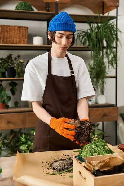 Young man with gloves transplants vibrant plants on a stylish workspace surrounded by nature. — Stock Photo