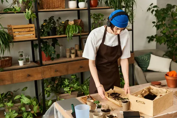 Handsome young man diligently working with soil and plants in an artistic studio setting. — Stock Photo
