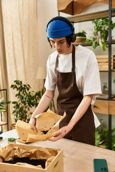 Handsome young man focuses on transplanting plants, showcasing his passion for gardening indoors. — Stock Photo