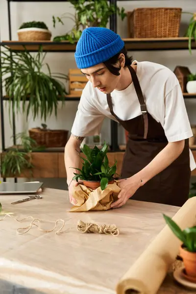 Handsome young man is carefully transplanting plants while surrounded by a serene studio atmosphere. — Stock Photo