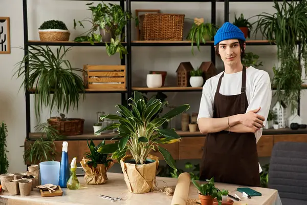 Young man posing near a lush plant in a creative studio filled with greenery. — Stock Photo