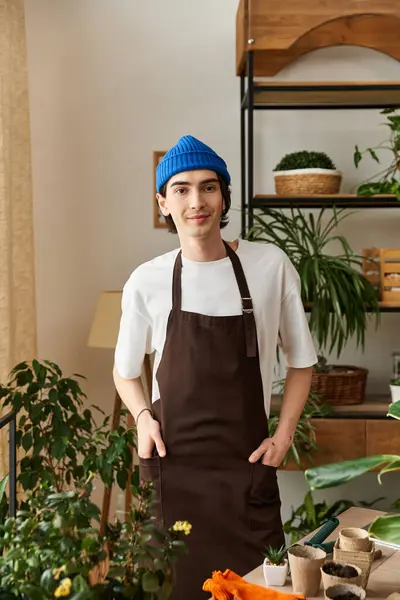 Handsome young man looking at camera among plants in a bright studio. — Stock Photo