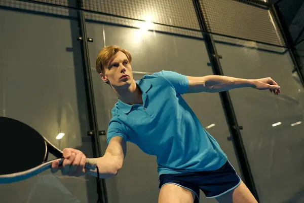 A young man in sportswear intensely plays padel, demonstrating athletic skill on the court. — Stock Photo