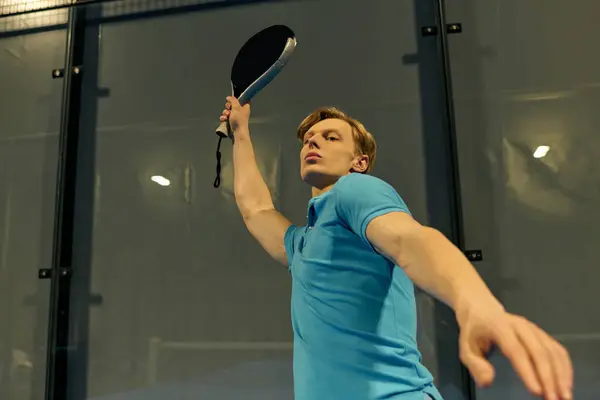 A young man in sportswear skillfully serves during an intense padel game on the court. — Stock Photo