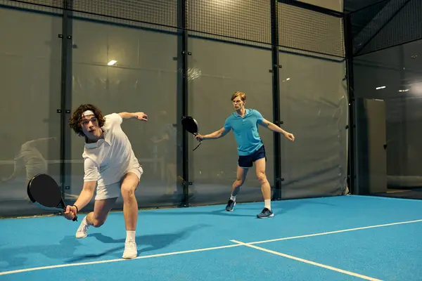 Two young sportsmen showcase their skills playing padel in an indoor arena. — Stock Photo