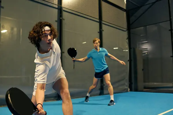 Two young men engage in a competitive padel match, demonstrating teamwork and skill. — Stock Photo