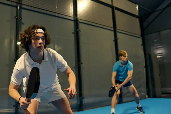 Two young men focus intensely as they prepare for an exciting game of padel indoors. — Stock Photo