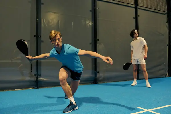 Two young men engage in an exciting game of padel, demonstrating their athleticism and teamwork. — Stock Photo