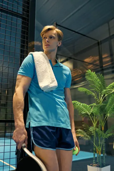 Athletic young man relaxes by the padel court, towel on shoulder, ready to play. — Stock Photo