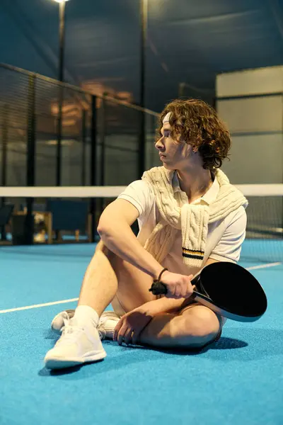 An athletic young man resting after padel game on a vibrant court. — Stock Photo