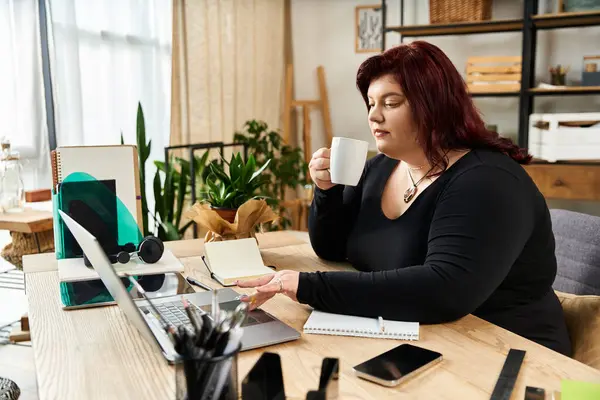Pretty woman enjoys a warm drink while brainstorming artistic ideas in her chic studio. — Stock Photo