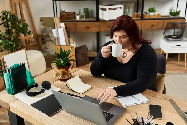 Mujer elegante sorbe café y se centra en sus tareas creativas en un espacio de estudio bellamente diseñado. - foto de stock