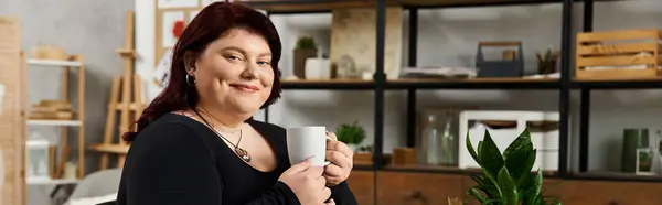 Pretty woman relaxes with a cup of tea in a chic art studio, radiating creativity and inspiration. — Stock Photo