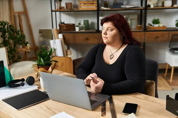 Elegant woman sits thoughtfully at her workspace, exploring her creative ideas in a vibrant studio. — Stock Photo