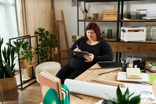 A girl sketches ideas in a vibrant studio filled with plants. — Stock Photo