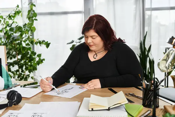 In a bright art studio, a pretty woman diligently sketches, surrounded by plants and artistic tools. — Stock Photo