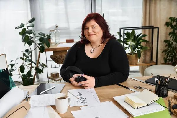 Eine selbstbewusste Frau sitzt in einem friedlichen Kunstatelier, umgeben von Skizzen, Pflanzen und kreativen Werkzeugen. — Stockfoto