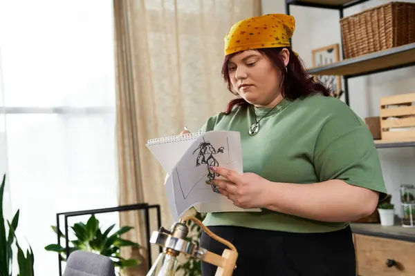 Hübsche Frauenskizzen in ihrem kreativen Atelier, umgeben von viel Grün und künstlerischen Elementen. — Stockfoto