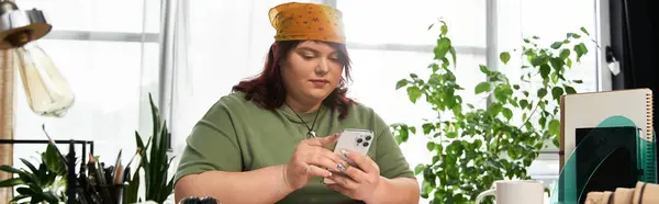 Chic woman engages with her phone in a bright art studio, surrounded by greenery and artistic tools. — Stock Photo