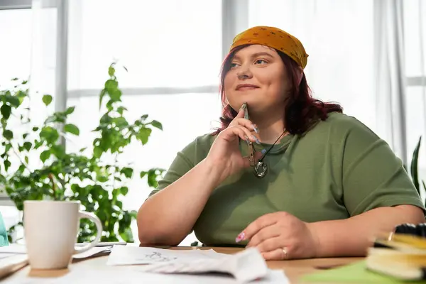 Una mujer elegante se sienta en un estudio de arte brillante, reflexionando sobre su próximo movimiento creativo mientras bosqueja. - foto de stock