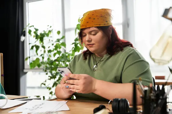 A chic woman engages with her phone amidst artistic tools, expressing creativity in a bright studio. — Stock Photo