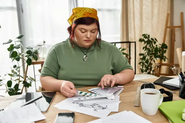 An elegant woman chooses color palettes in a sunlit art studio with lush plants. — Stock Photo