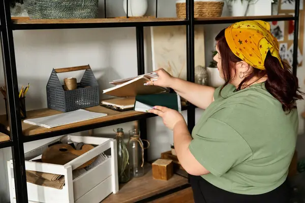 A pretty woman organizes her creative workspace, surrounded by art supplies and inspiration. — Stock Photo