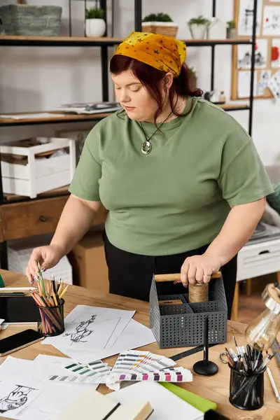 Una mujer elegante se involucra profundamente en su proceso creativo rodeado de suministros de arte en un estudio. - foto de stock