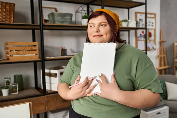 A stylish woman holds a sketchpad, embodying creativity in her inspiring art studio. — Stock Photo