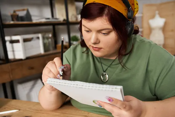 Una mujer elegante se centra en dibujar en su estudio de arte, mostrando su talento creativo. - foto de stock