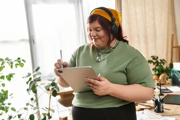 Una mujer bonita dibuja ideas con una tableta en un estudio de arte brillante, rodeado de inspiración. - foto de stock