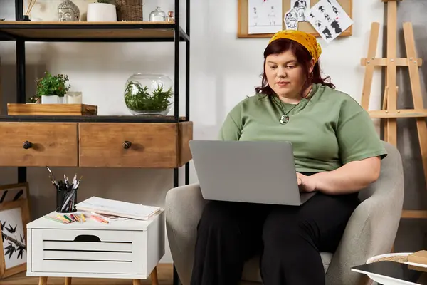 Woman works thoughtfully on laptop in chic studio filled with art supplies and sketches — Stock Photo