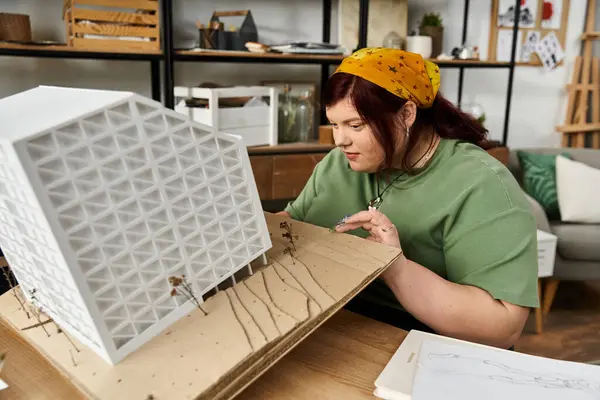 A pretty woman showcases her creativity by building an architectural model in a chic studio. — Stock Photo