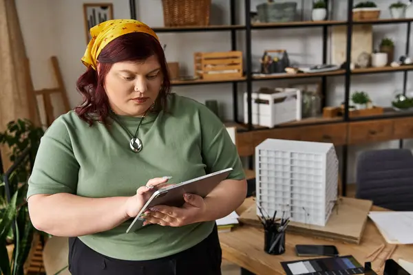 An elegant woman explores her creativity in an art studio, focused on her tablet and tools. — Stock Photo