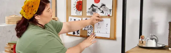 Elegant woman passionately arranges her inspiring artwork on a studio wall, showcasing creativity. — Stock Photo