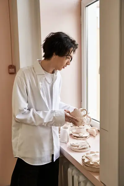 A talented man examines his ceramic creations in a bright pottery studio filled with inspiration. — Stock Photo