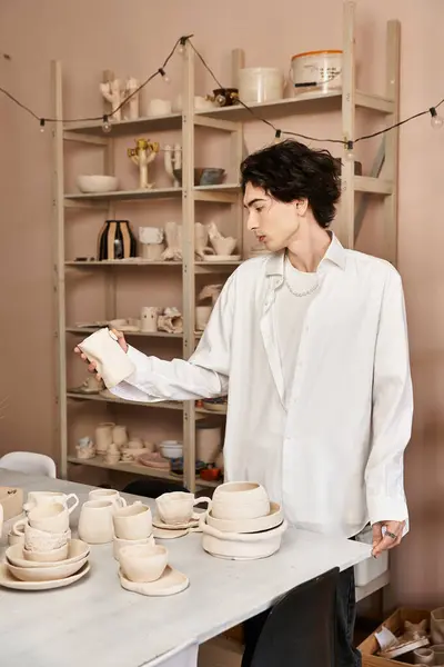 Stylish man engages in ceramics, surrounded by beautiful pottery creations and artistic tools. — Stock Photo
