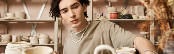 A skilled young man passionately crafts pottery in a well organized ceramics studio. — Stock Photo