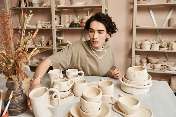 A talented artist skillfully arranges handmade pottery pieces in a bright, inspiring studio. — Stock Photo