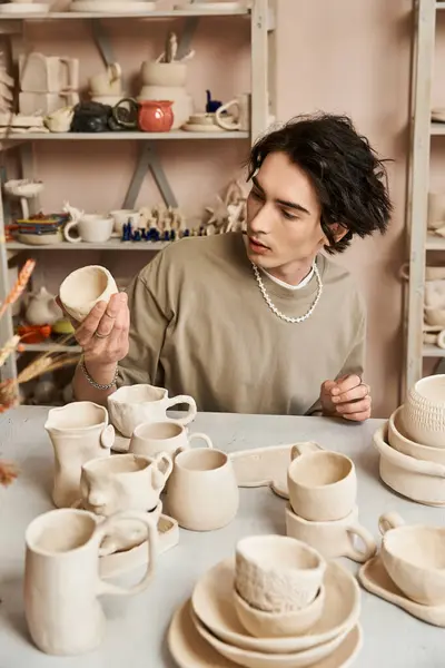 A creative man showcases unique pottery pieces in a vibrant studio. — Stock Photo
